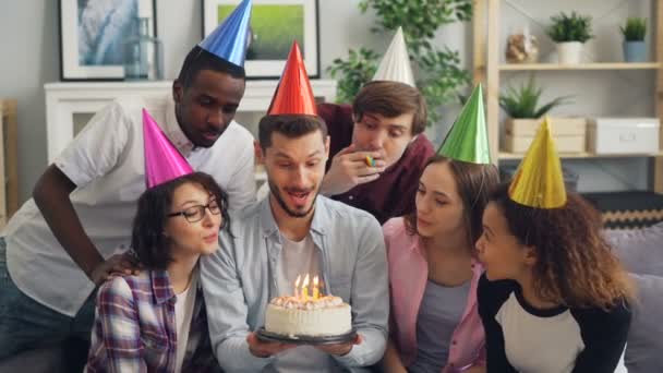 Cara feliz cantando com amigos, em seguida, fazendo desejo soprando velas no bolo de aniversário — Vídeo de Stock