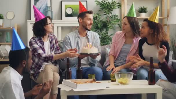 Друзья, празднующие день рождения, задувают свечи на торте, пьют и веселятся — стоковое видео