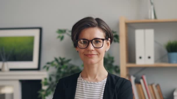 Portret van mooie jonge vrouw glimlachend kijken naar camera staande in kantoor — Stockvideo