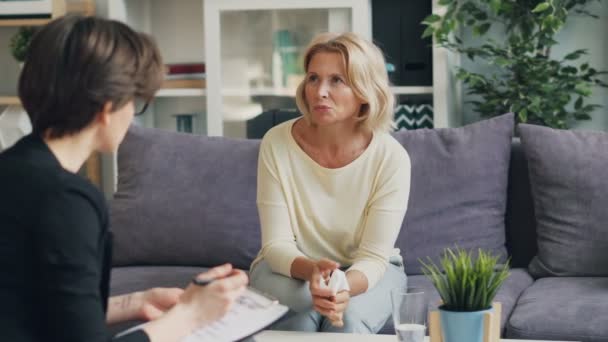 Mature woman talking to female psychologist sitting on couch in modern office — Stock Video