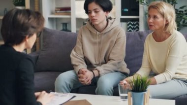 Anne ve genç oğlu ofiste psikolog sarılma ve gülümseyerek konuşurken