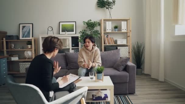 Zoom em de criança adolescente discutindo a vida falando com o psicologista sentado no escritório — Vídeo de Stock
