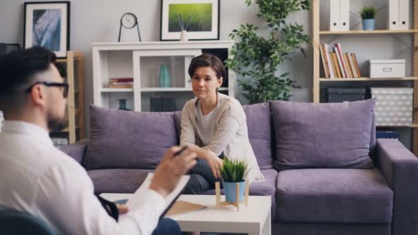 Männlicher Psychologe im Gespräch mit hübscher junger Patientin während einer Sitzung im Büro — Stockvideo