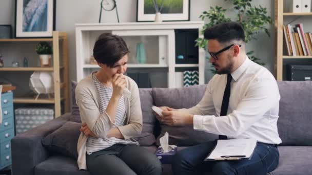 Terapeuta útil reconfortando a la mujer estresada llorando en la oficina dando papel tisú — Vídeos de Stock