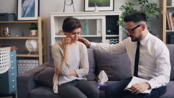 Omtänksam psykolog hjälpa gråtande kvinna ger papper vävnad röra skuldra — Stockvideo