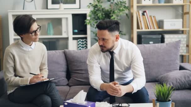 Young woman psychologist talking to depressed businessman during session — 비디오