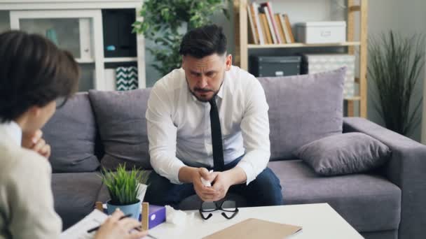 Unhappy guy stressed businessman speaking with psychologist in office — Stock Video