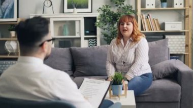 Neşeli obez kadın seans sırasında klinikte erkek psikolog konuşuyor