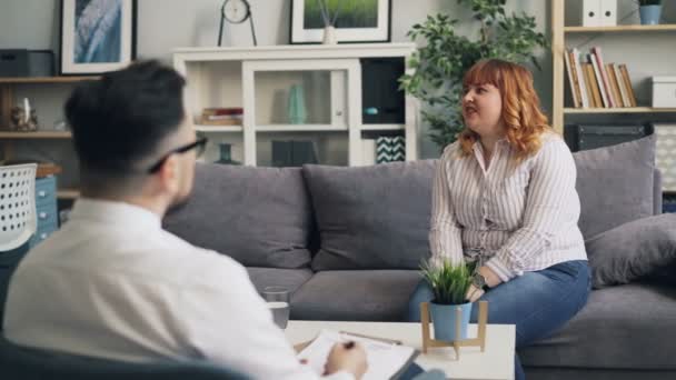 Емоційна леді відкривається психологу в сучасному офісі, що говорить жест — стокове відео