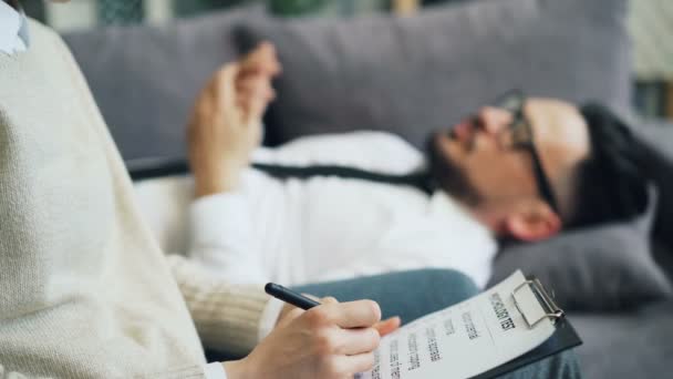 Nahaufnahme von Psychologen beim Schreiben und männlichen Patienten beim Beantworten von Fragen im Büro — Stockvideo