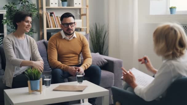Vrolijke paar man en vrouw glimlachend praten met psychotherapeut tijdens counseling — Stockvideo