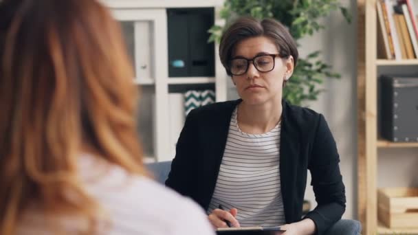 Vellykket psykolog konsulterer kvindelig patient på kontoret taler skriftligt – Stock-video
