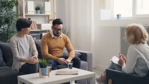 Злий чоловік і дружина сваряться в кабінеті психотерапевта під час розмови — стокове відео