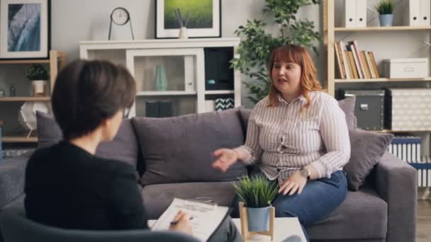 Нещасна леді з надмірною вагою відкривається психологу в сучасному офісі — стокове відео