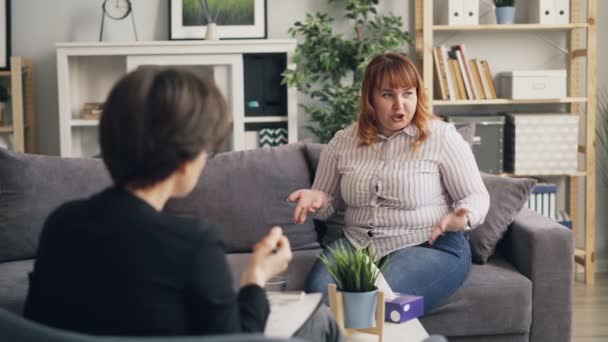 Unhappy obese woman telling psychologist about personal problems during session — Stock Video