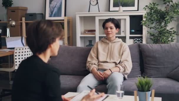 Tiener jongen in trendy kleding luisteren naar psycholoog zittend in Office — Stockvideo