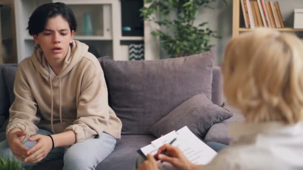 Мальчик-подросток, проходящий психологическую оценку, беседует с терапевтом в офисе — стоковое видео