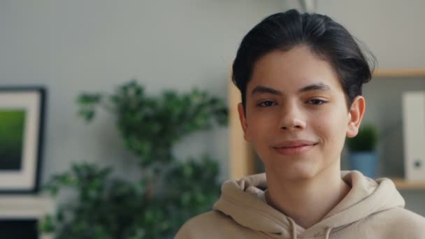 Close-up retrato de menino adolescente atraente sorrindo olhando para a câmera em casa — Vídeo de Stock