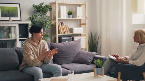 Nieszczęśliwy nastolatek mając rozmowę z doświadczonym terapeutą w biurze — Wideo stockowe