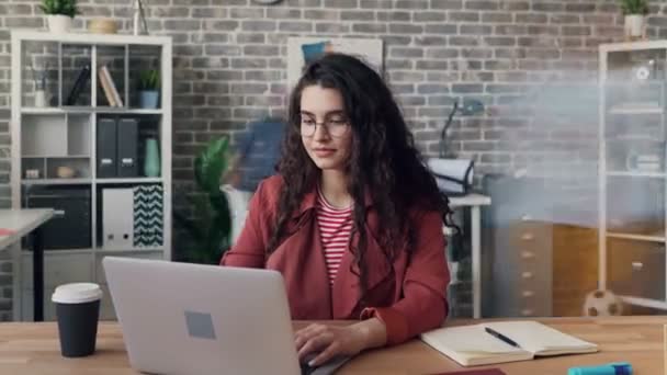 Zoom out time-lapse της νεαρής κυρίας χρησιμοποιώντας φορητό υπολογιστή στο κοινόχρηστο γραφείο επικεντρώθηκε στην εργασία — Αρχείο Βίντεο