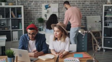 Modern ofiste konuşan dizüstü bilgisayar ile çalışan şapkalar kız ve adam hipsters