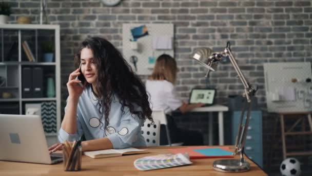 Kadın iş sahibi dizüstü bilgisayar kullanarak sipariş ofis cep telefonu konuşuyor — Stok video