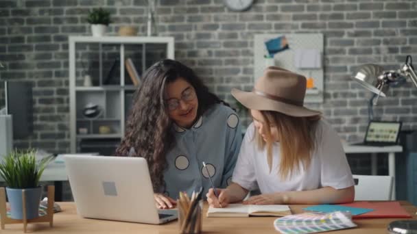 Creatieve ontwerpers schrijven in notebook dan werken met laptop in Office — Stockvideo