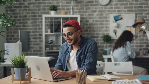 Bonito cara trabalhando com laptop no escritório compartilhado criativo ocupado com o projeto — Vídeo de Stock