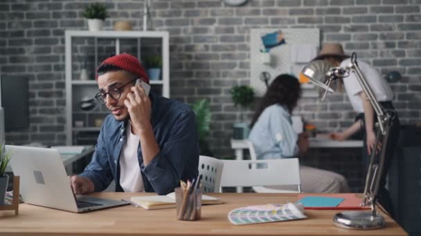 Pemilik bisnis melakukan panggilan dengan smartphone duduk di meja di kantor kreatif — Stok Video