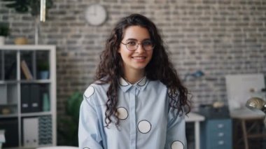 Güzel kadın çalışanın kameraya bakıp ofiste gülümseyen portresi