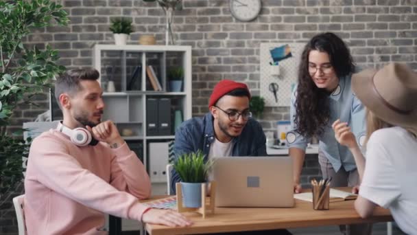 Les membres de l'équipe parlent et gestualisent en regardant l'écran d'ordinateur portable dans le bureau créatif — Video