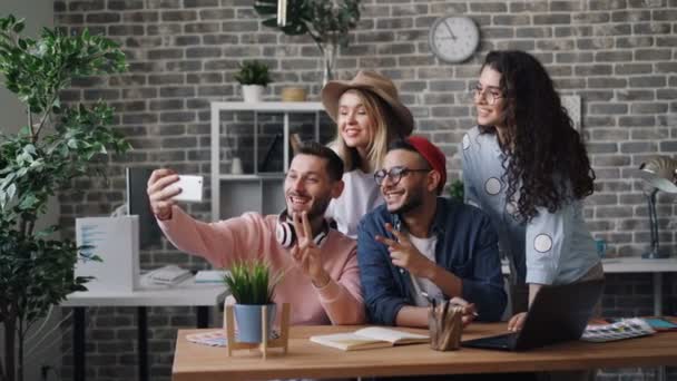 Equipo de negocios tomando selfie en la oficina usando la cámara del teléfono inteligente posando sonriendo — Vídeos de Stock