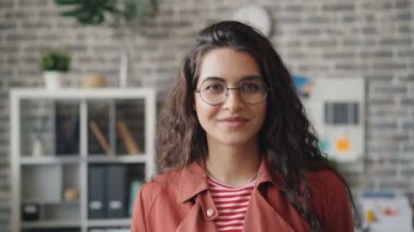 Modern ofiste ayakta gülümseyen çekici genç bayan Yavaş çekim portre