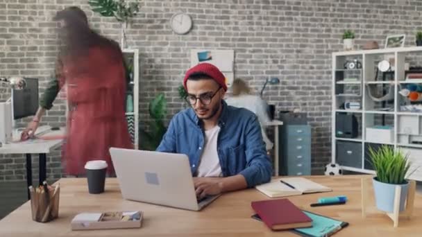 Zoom in time-lapse van creatieve man die werkt op kantoor met behulp van laptop op het bureau — Stockvideo