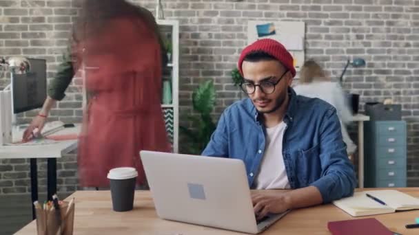 Zeitraffer eines viel beschäftigten Mannes mit Laptop im Büro, während Kollegen herumhetzen — Stockvideo