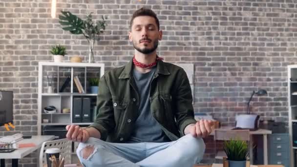 Zoom out time-lapse of entrepreneur relaxing at work in lotus position on desk — 비디오