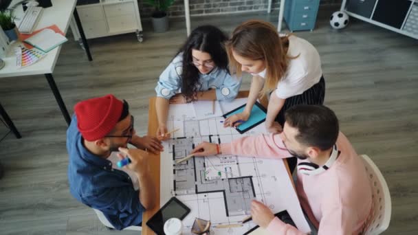 Equipo creativo discutiendo proyecto en el trabajo mirando documentos y luego levantando armas — Vídeos de Stock