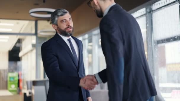 Hombres barbudos empresarios se reúnen en la cafetería estrechando la mano y hablando juntos — Vídeos de Stock