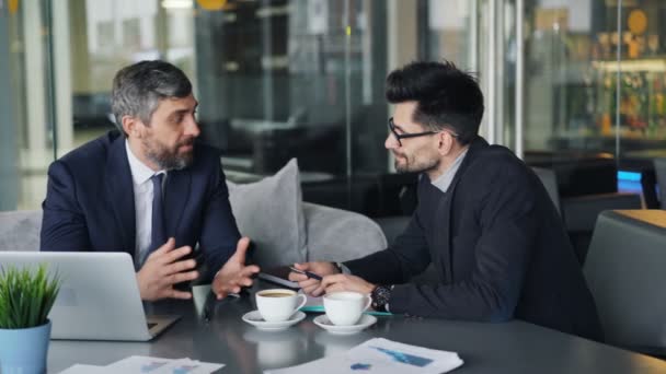 Empresários maduros conversando e rindo no café durante as negociações — Vídeo de Stock