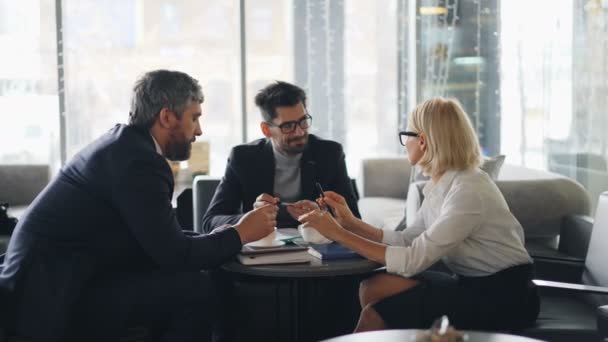 Empresária sênior fazendo oferta de negócios para sócios em café falando gestos — Vídeo de Stock