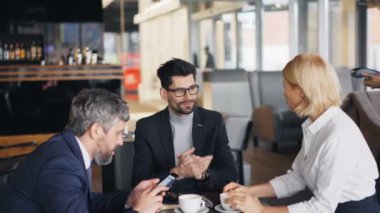 Modern akıllı telefon kullanarak kafede öğle yemeği için ödeme işadamları grubu