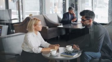 İş arkadaşları erkek ve kadın öğle yemeği molası sırasında kafede konuşan gesturing konuşan