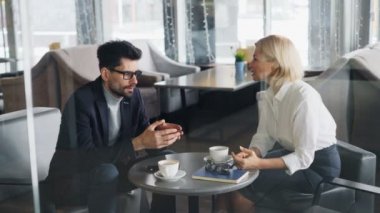 Orta yaşlı sakallı adam kafede kadın iş ortağı ile anlaşma tartışıyor