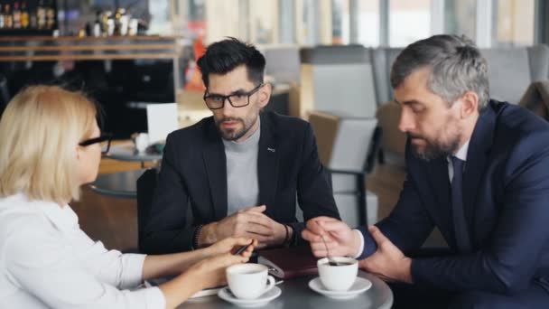 Empresario guapo hablando con gente de negocios de éxito en café moderno — Vídeo de stock