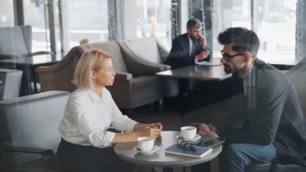 Coworkers uomo e donna che parlano nel caffè durante la pausa pranzo parlando gesticolando — Video Stock