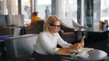Neşeli kadın girişimci kafede el sallayarak konuşurken online görüntülü arama yapma