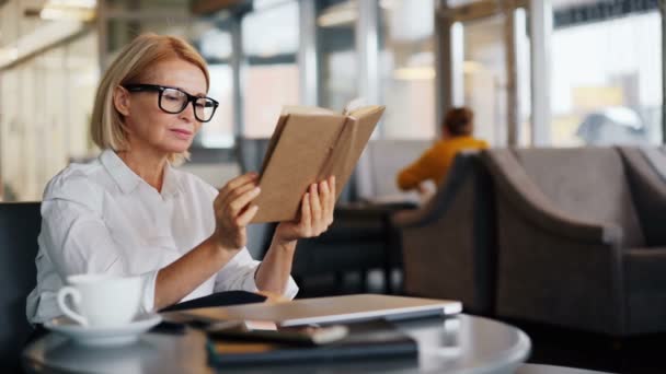Intelligent businesswoman enjoying book reading in cafe during coffee break — Stock Video