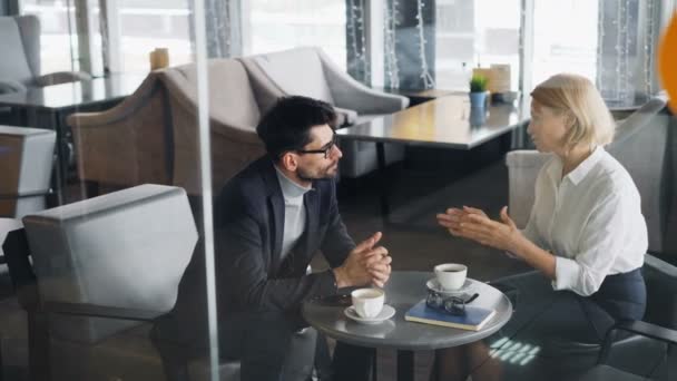 Entrepreneurs mature homme et femme parler assis à la table dans le café ensemble — Video