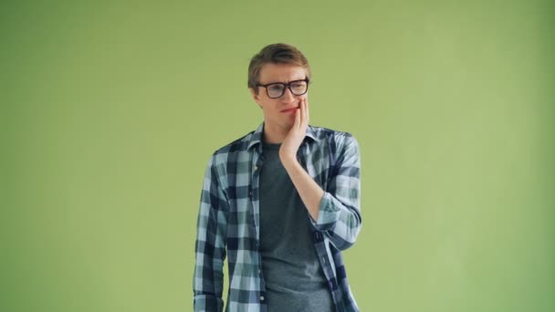 Portret van een jonge man die lijdt aan een tandpijn die de Wang met een triest gezicht aanraakt — Stockvideo