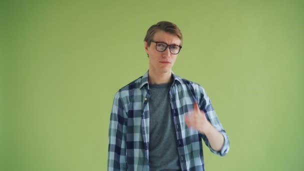 Portret van knappe hipster zwaaiende een kus en glimlachend op groene achtergrond — Stockvideo